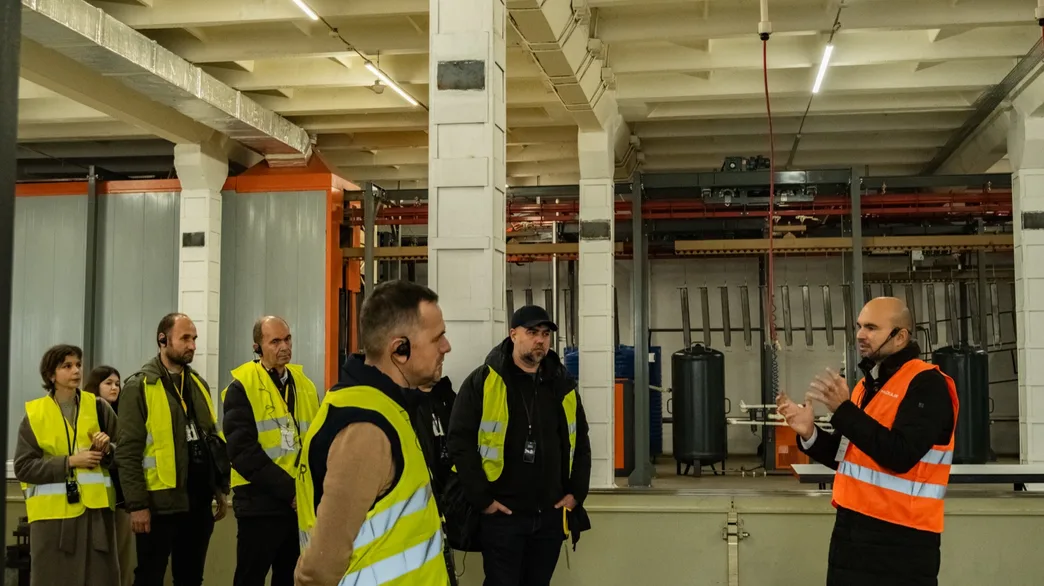 Ghidul prezentând o linie de producție grupului în hala de asamblare